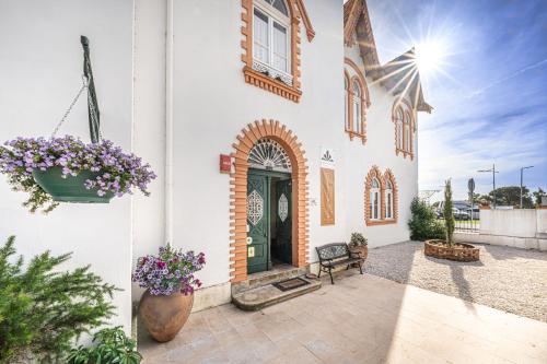 a white building with a green door and flowers at Dona Amélia in Abrantes