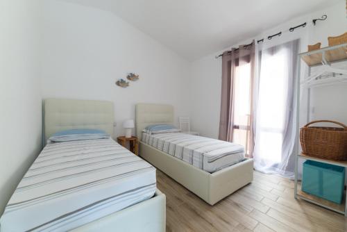 Duas camas num quarto branco com uma janela em villa aloe 2 em Costa Paradiso