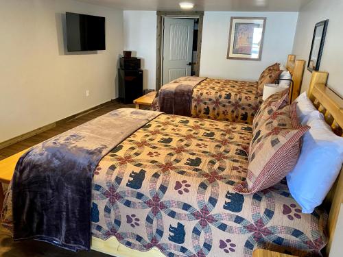 a hotel room with two beds and a television at Island Park Lodge in Island Park
