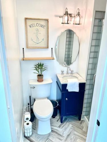 a bathroom with a toilet and a sink and a mirror at Buttonwood Boutique Hotel in West Cape May