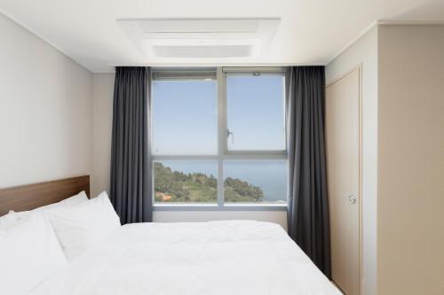 a bedroom with a bed and a large window at Donghae Oceancity Residence Hotel in Donghae