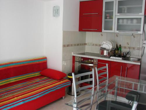 una pequeña cocina con armarios rojos y un sofá rojo en Villa Bruna Apartment, en Rab