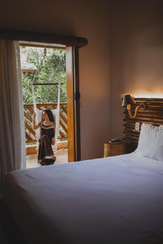 a woman sitting on a swing in a hotel room at VillaMag in Jericoacoara