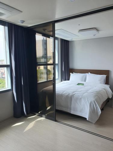 1 dormitorio con cama y espejo grande en Donghae Oceancity Residence Hotel, en Donghae