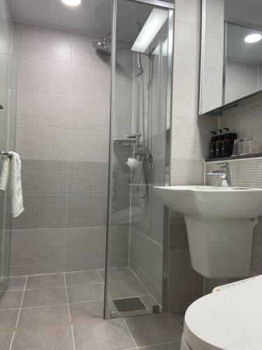 a bathroom with a glass shower and a sink at Donghae Oceancity Residence Hotel in Donghae