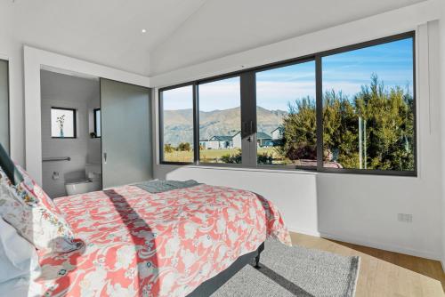 a bedroom with a bed and a large window at Bull Ridge Escape - Wanaka Holiday Home in Wanaka