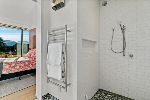 een witte badkamer met een douche en een bed bij Bull Ridge Escape - Wanaka Holiday Home in Wanaka