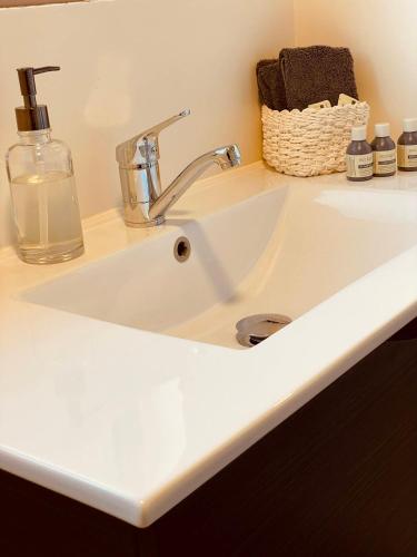 a white sink with a soap bottle and a basket at Stay Kerikeri in Kerikeri