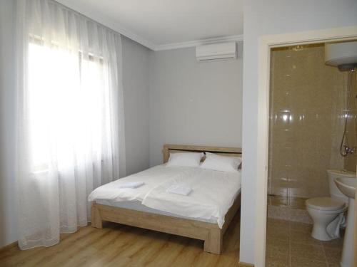 1 dormitorio con cama, aseo y ventana en Narsou Guest House, en Gudauta