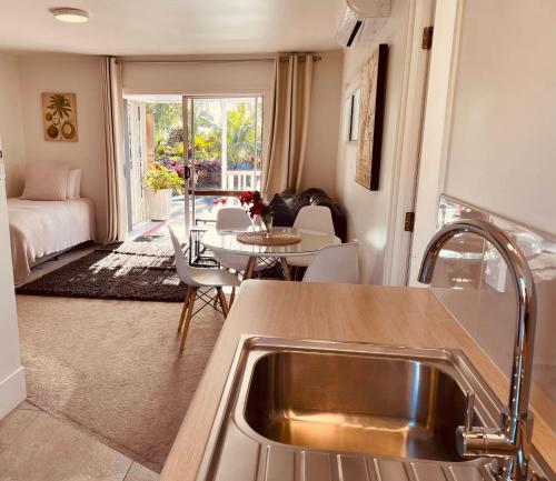 a kitchen and living room with a sink and a table at Stay Kerikeri in Kerikeri