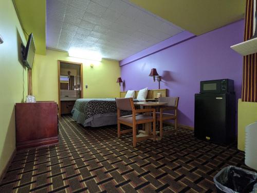 a hotel room with a bed and a desk with a table at Great Plains Budget Inn in Lincoln