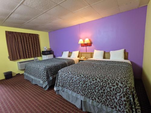 a hotel room with two beds and a purple wall at Great Plains Budget Inn in Lincoln