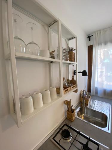 a kitchen with a sink and white cabinets with dishes at Casa Vacanze Giorgetta Palazzina privata di due piani in Chioggia