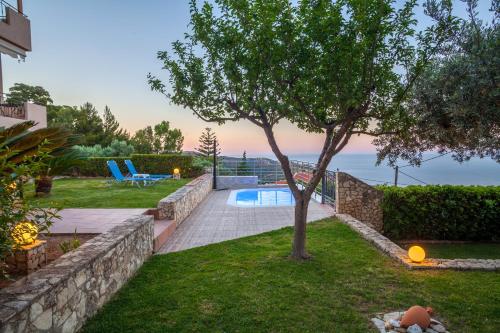 een achtertuin met een boom en een zwembad bij Panorama Traditional House With Private Pool in Rodhiá