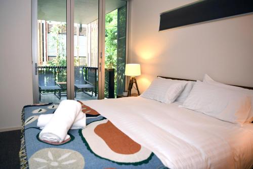 a bedroom with a bed with white sheets and pillows at Private Retreat in the heart of Noosa in Noosa Heads