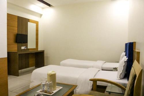 a room with a bed and a table and a tv at Hotel Apex Inn in Vapi