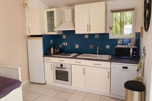a kitchen with white cabinets and a white refrigerator at le Studio charme et tranquillité in Plan-de-la-Tour