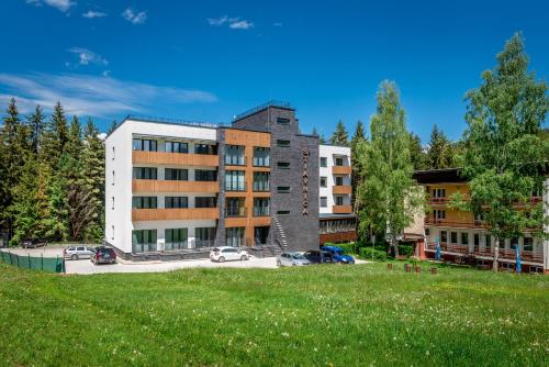a building with cars parked in a parking lot at Apartmánový dom Štiavnica in Liptovský Ján