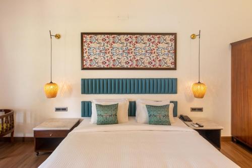 a bedroom with a large white bed with blue pillows at Green Meadows Resort in Chennai
