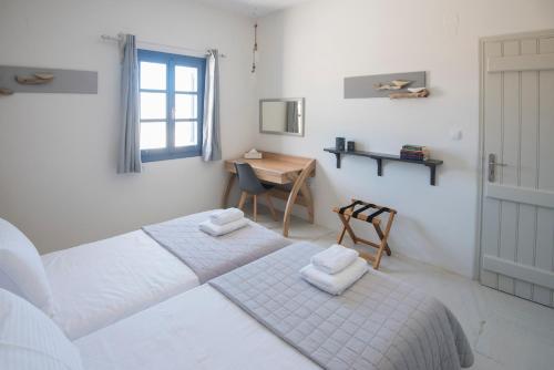 a white bedroom with two beds and a desk at KYMA Seafront Exceptional 2BD house in Naousa in Naousa