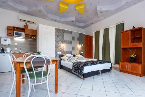 a bedroom with a bed and a table and a kitchen at Central Apartman in Gyula