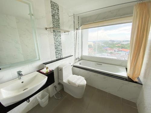 een badkamer met een wastafel, een toilet en een raam bij Vareena palace hotel in Noord Pattaya