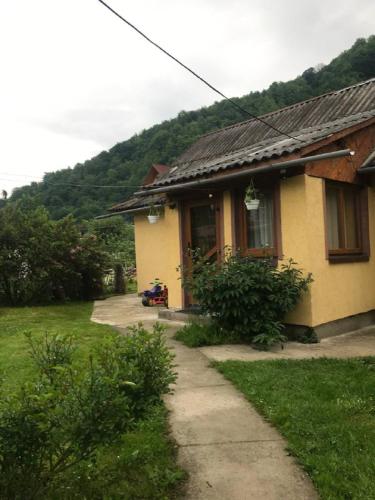 a small yellow house with a sidewalk in front of it at Підскельний in Yaremche