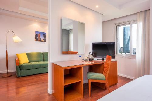 a room with a desk with a computer and a couch at Hotel Madrid Chamartín, Affiliated by Meliá in Madrid