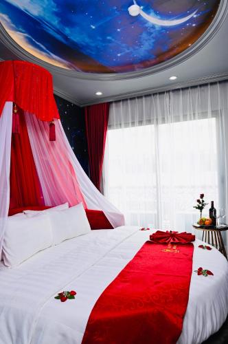 a bedroom with a red and white bed with a ceiling at Lavie Hotel in Hanoi