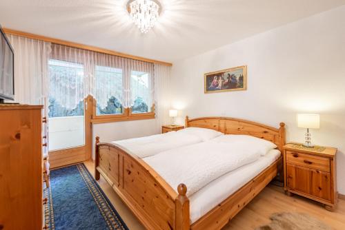 a bedroom with a wooden bed and a chandelier at Apartment Balma 3 rooms in Zermatt