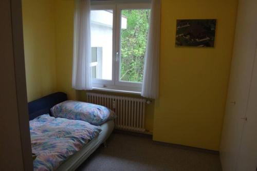 um pequeno quarto com uma cama e uma janela em Wohnung mit See Sicht in Carona em Carona