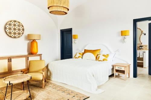 a white bedroom with a bed and a chair at Masseria Calderisi in Savelletri di Fasano
