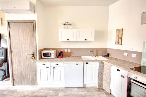 a kitchen with white cabinets and a sink at L'Escapade à Lascaux in Montignac