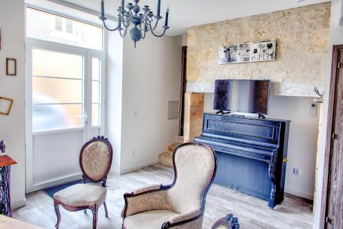 a living room with a piano and two chairs at L'Escapade à Lascaux in Montignac