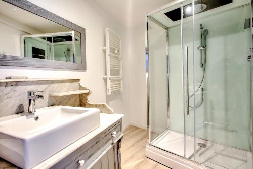 a white bathroom with a sink and a shower at L'Escapade à Lascaux in Montignac