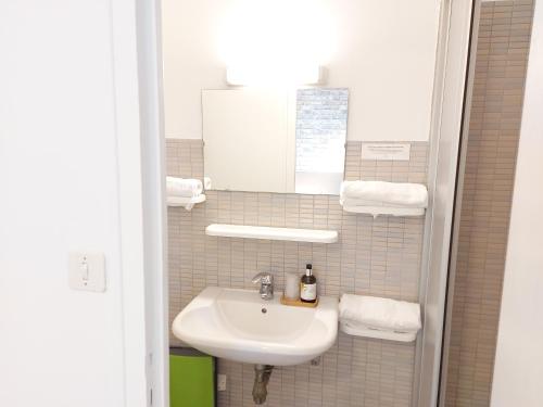 a bathroom with a sink and a mirror and towels at Logis Hôtel Vannes Nord Le Clos Des Hortensias in Locqueltas