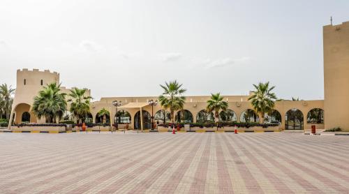 a large courtyard with palm trees in front of a building at Dhafra Beach Hotel in Jebel Dhanna
