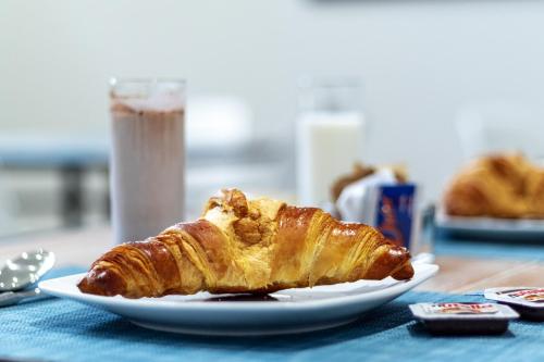 a plate of pastry on a table with a glass of milk at Hotel Portum in Giardini Naxos