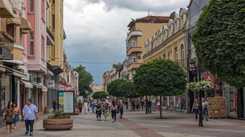 a group of people walking down a street with buildings at Plovdiv City Center Hotel in Plovdiv