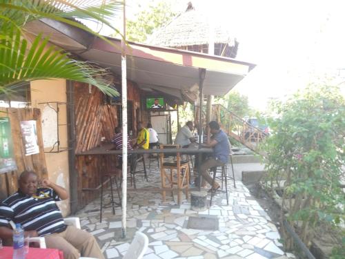 a group of people sitting outside of a restaurant at Kicec bar and guest house airport in Dar es Salaam