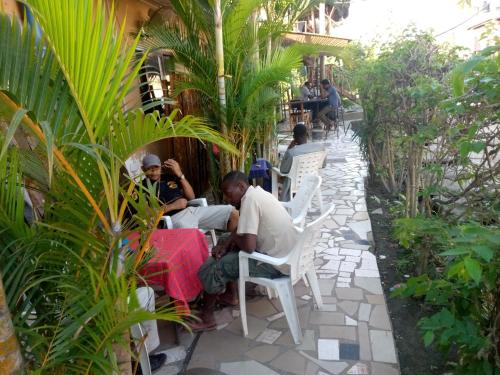 a group of people sitting at a table in a garden at Kicec bar and guest house airport in Dar es Salaam