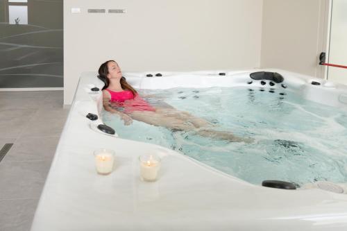 a woman sitting in a bath tub with candles at Hotel & Wellness Stella Delle Langhe in Govone
