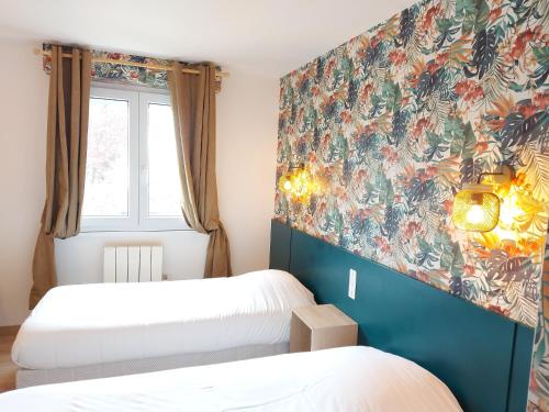 a bedroom with two beds and a floral wall at Logis Hôtel Vannes Nord Le Clos Des Hortensias in Locqueltas