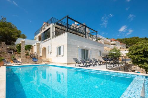 a villa with a swimming pool in front of a house at WATERFRONT SEA DREAM VILLA in Milna