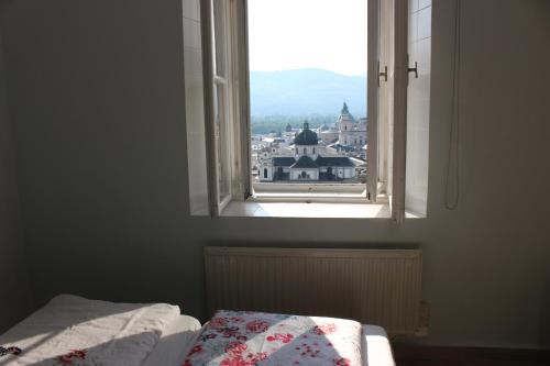 a bedroom with a window with a view of a city at Stadtalm Naturfreundehaus in Salzburg