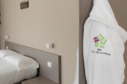 a towel hanging on a wall next to a bed at Hotel & Wellness Stella Delle Langhe in Govone