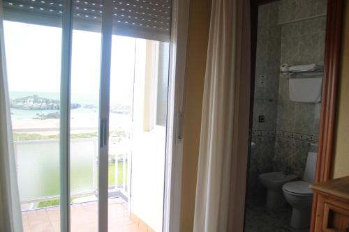 ein Badezimmer mit Toilette und Glasschiebetür in der Unterkunft Hotel Hoya in Noja