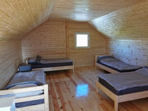 a room with three beds in a wooden cabin at Domki u Iwonki -brązowy in Niechorze