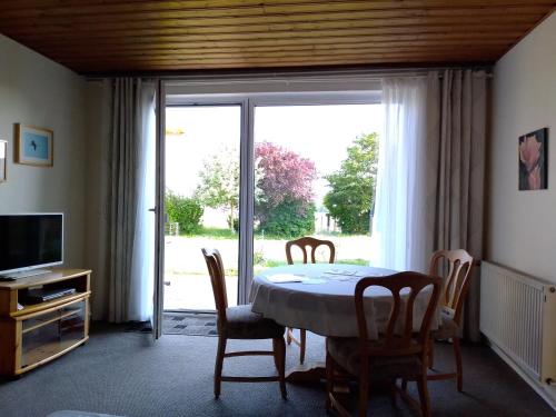 ein Esszimmer mit einem Tisch und Stühlen sowie einer Glasschiebetür in der Unterkunft Ferienwohnung Kraniche am Krakower See in Kuchelmiß