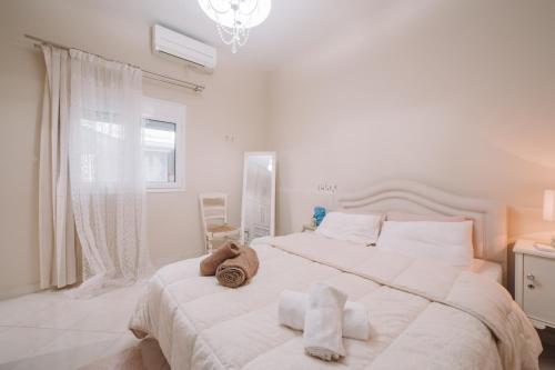 a white bedroom with a large bed with towels on it at Debbies House in Kalamata